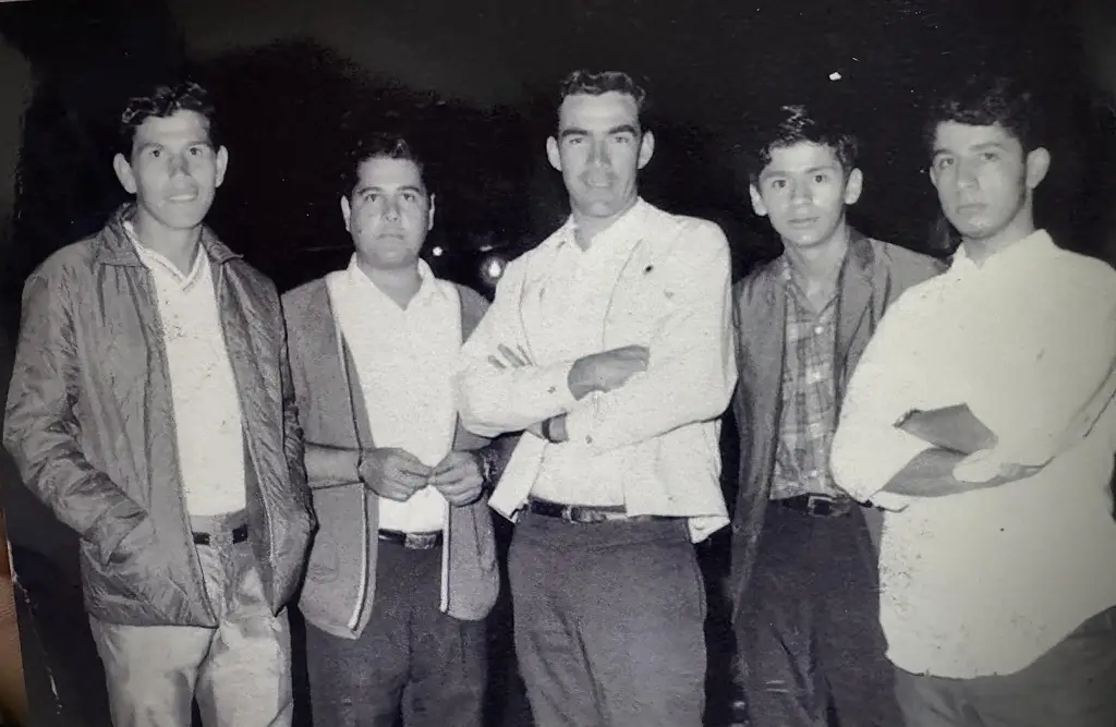 Grupo de cinco amigos alajuelenses en los años 70 u 80, posando juntos en una fotografía en blanco y negro.