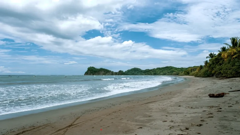 Vista panorámica de Playa Garza en Costa Rica, con arena limpia, oleaje suave y colinas verdes al fondo.