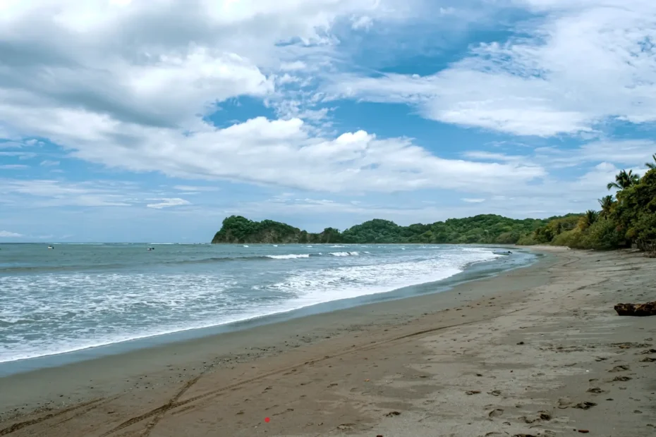 Vista panorámica de Playa Garza en Costa Rica, con arena limpia, oleaje suave y colinas verdes al fondo.