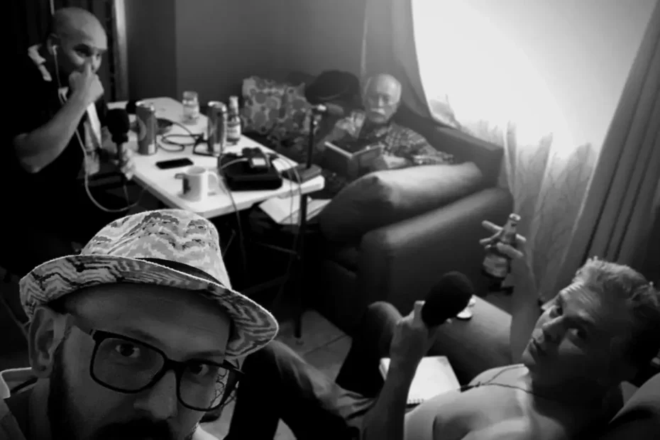Grupo de cuatro personas grabando un podcast en una sala, con micrófonos y bebidas sobre la mesa.