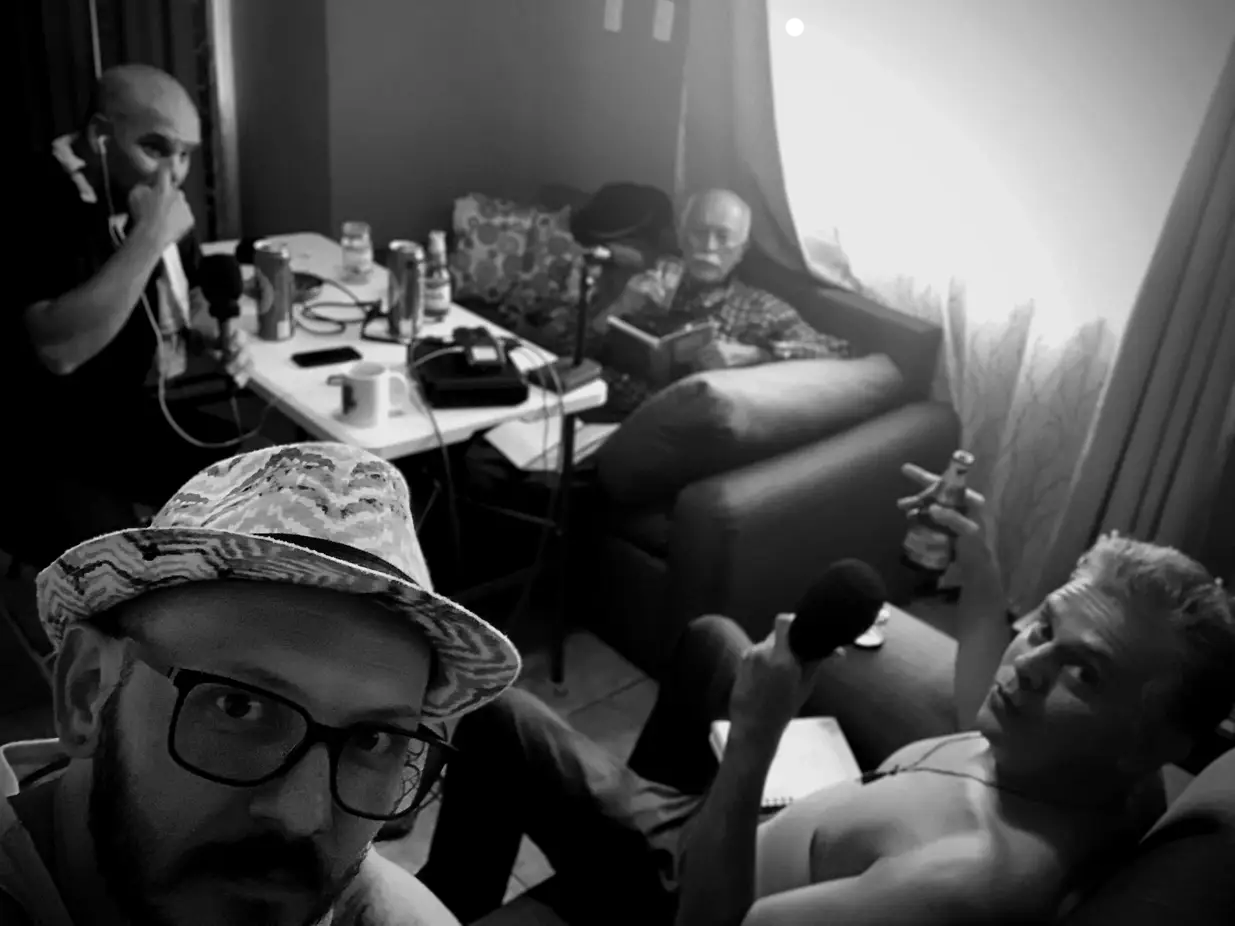 Grupo de cuatro personas grabando un podcast en una sala, con micrófonos y bebidas sobre la mesa.