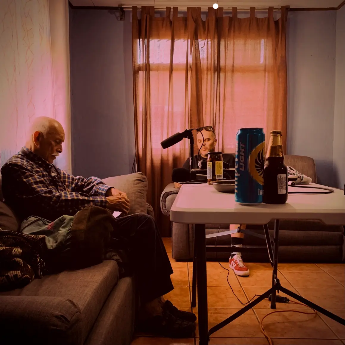 Dos personas en una sala grabando un podcast, con micrófono y bebidas en primer plano.