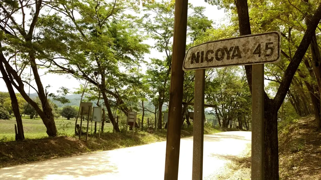 Carretera rural de tierra con rótulo oxidado que indica 45 kilómetros hacia Nicoya, Guanacaste.