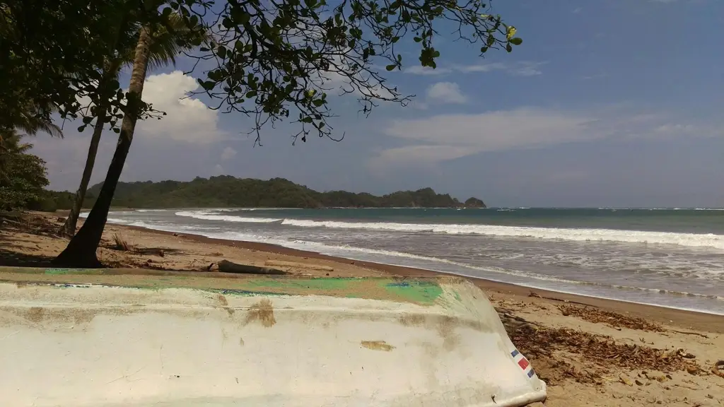 Bote dado vuelta sobre la arena en Playa Garza, con el mar y colinas verdes al fondo.