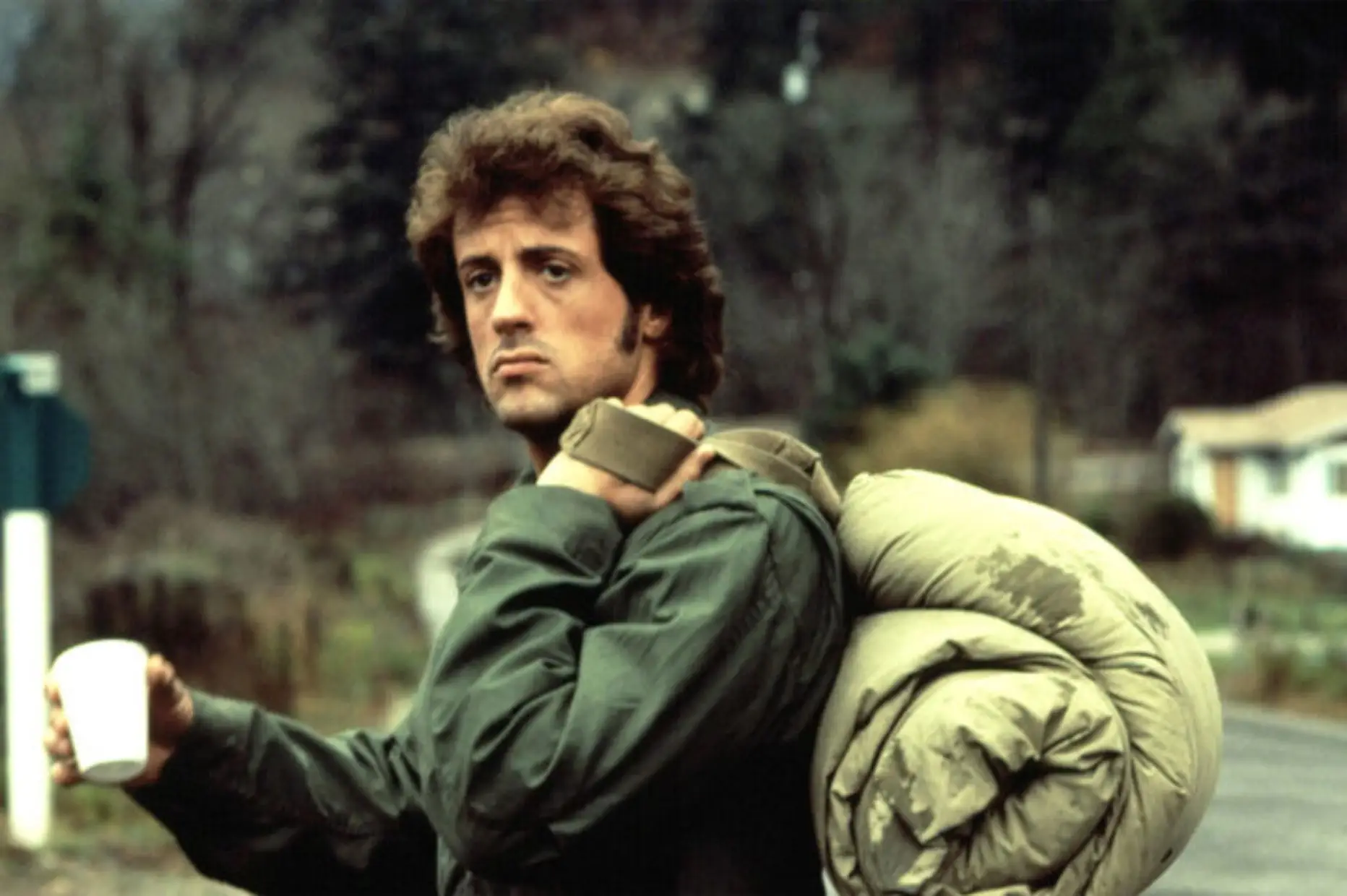 Joe Rambo con chaqueta M-65 cargando mochila de campaña.