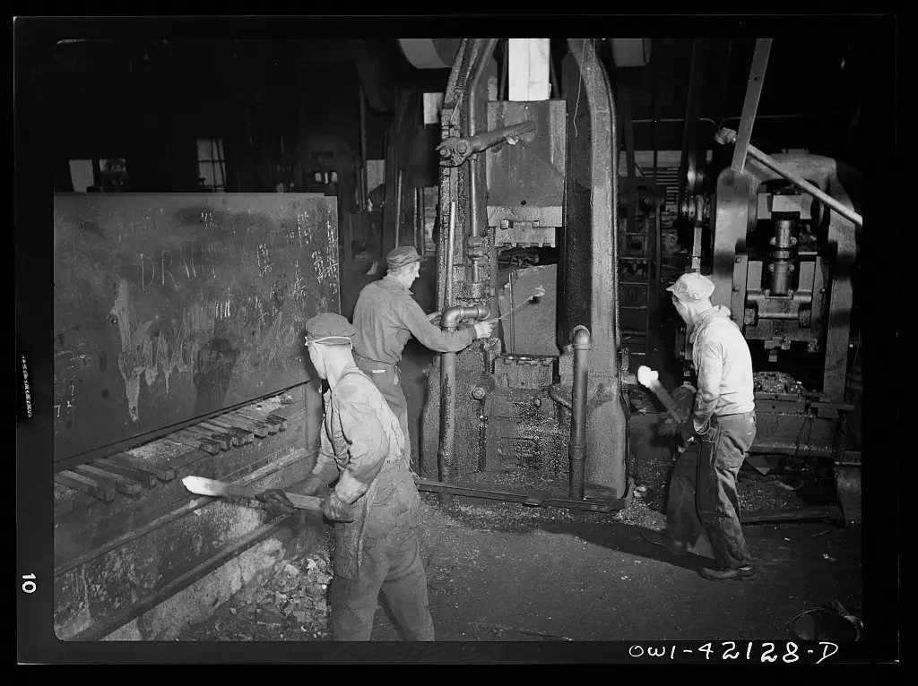 Obreros operando maquinaria pesada en una planta metalúrgica.