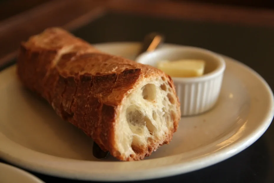 Pan francés servido con mantequilla sobre un plato blanco.