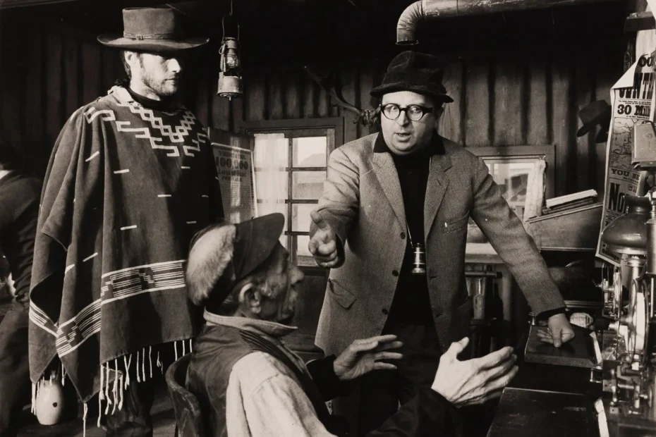 Sergio Leone dando indicaciones en set mientras Clint Eastwood observa caracterizado como Blondie.