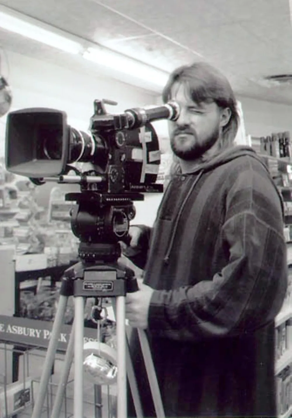 Kevin Smith mira por el visor de una cámara de cine montada en trípode, dentro de la tienda.