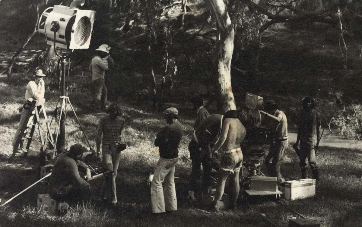 Equipo de rodaje en un bosque, con un reflector grande montado en un trípode.